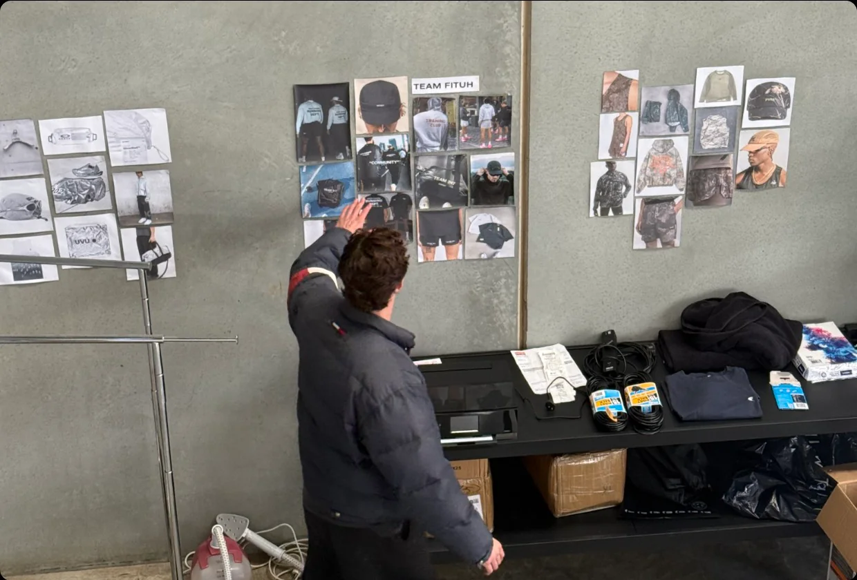 A founder pinning product photos to a moodboard wall in his studio